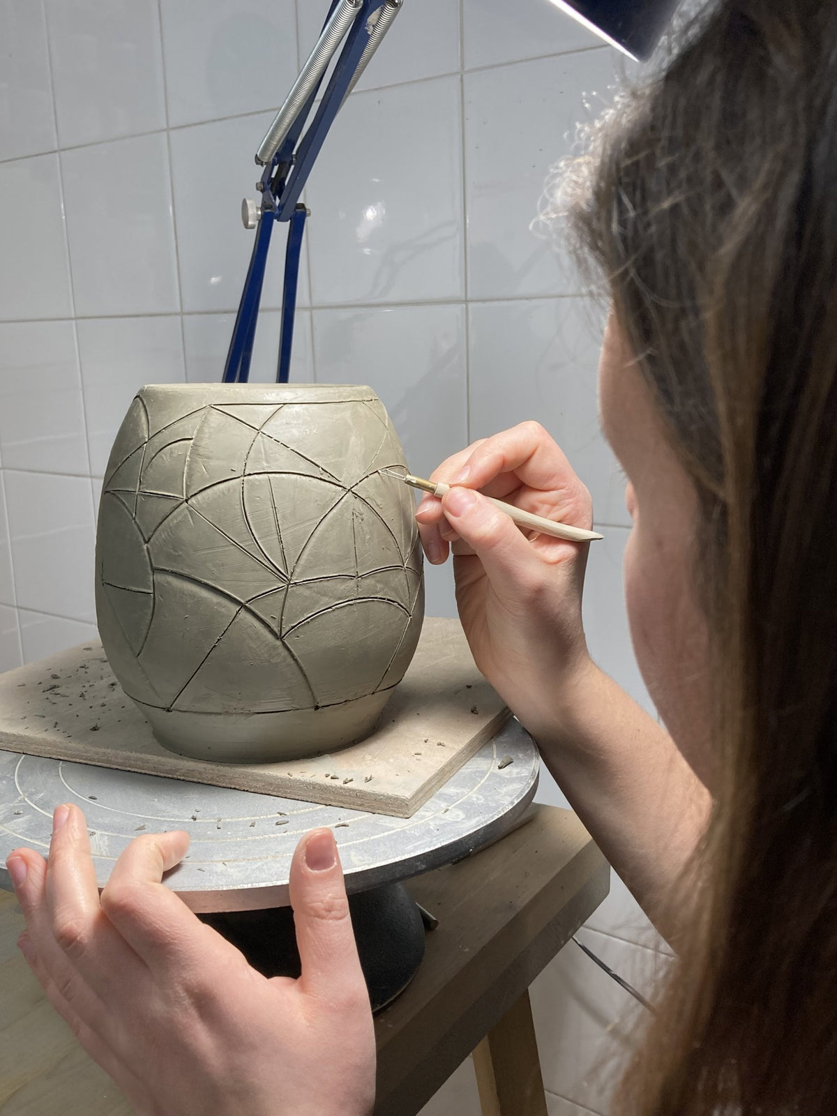Incisione di motivi geometrici su vaso in ceramica durante il corso di Ceramica Libera a Milano